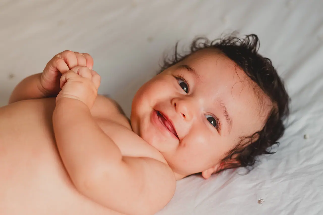 Fotografía de bautizo: bebe tumbado sonrisa