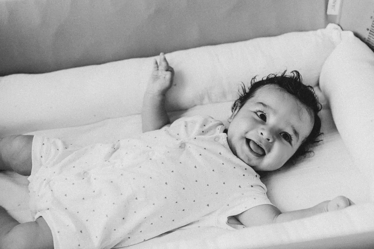 Fotografía de bautizo: bebe cuna risa, en blanco y negro