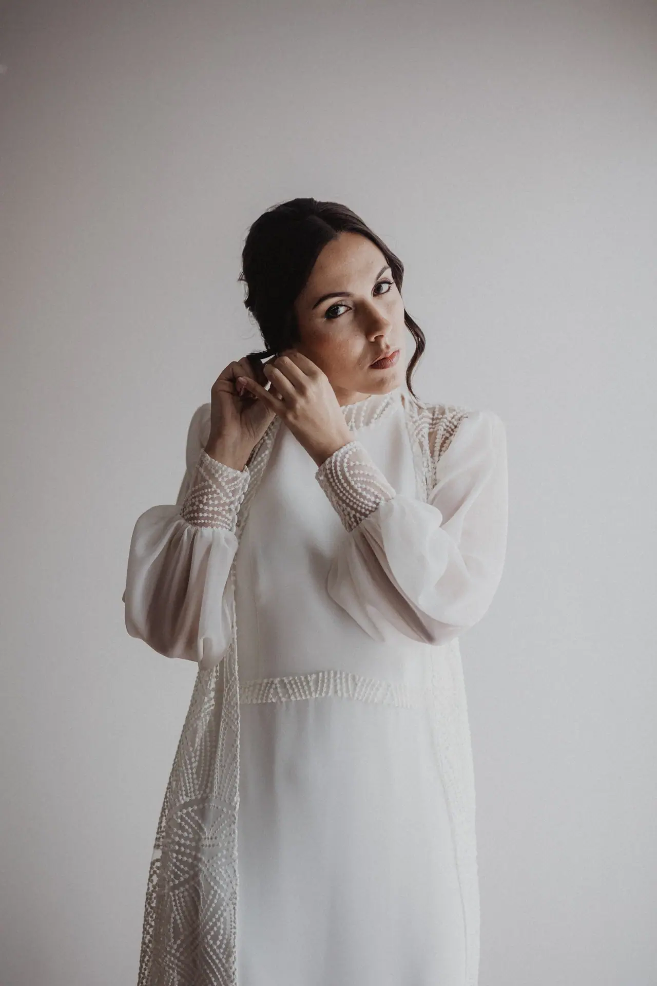 Fotografía de boda en Valencia: novia pendiente pared blanca
