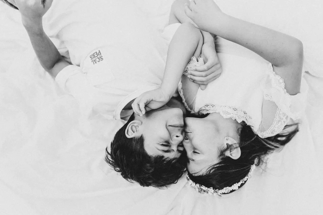 Fotografía de comunión: hermanos tumbados beso, en blanco y negro