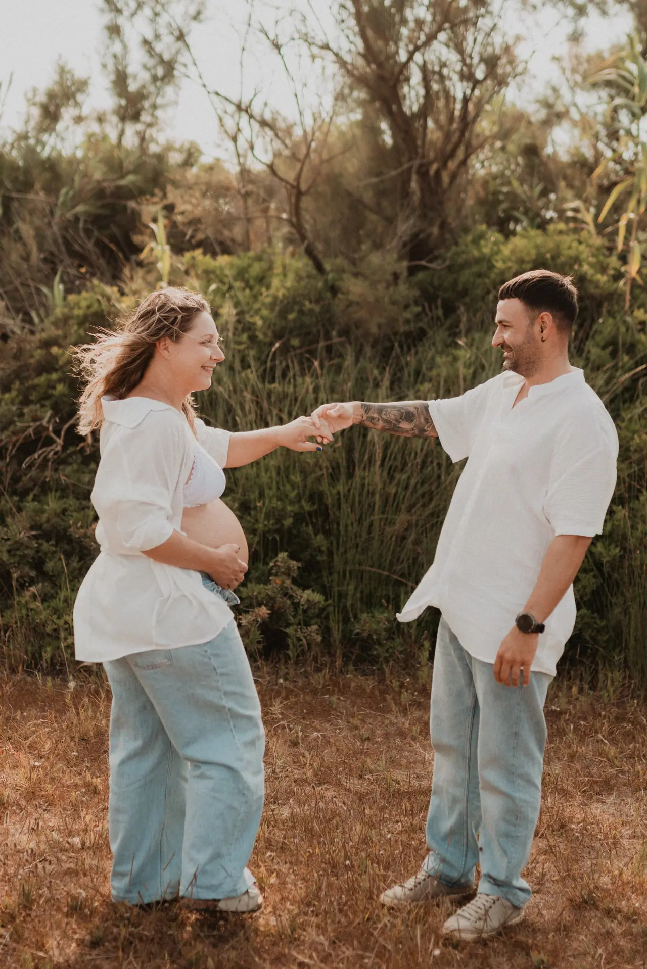 Pareja bailando en el campo en su sesión de embarazo