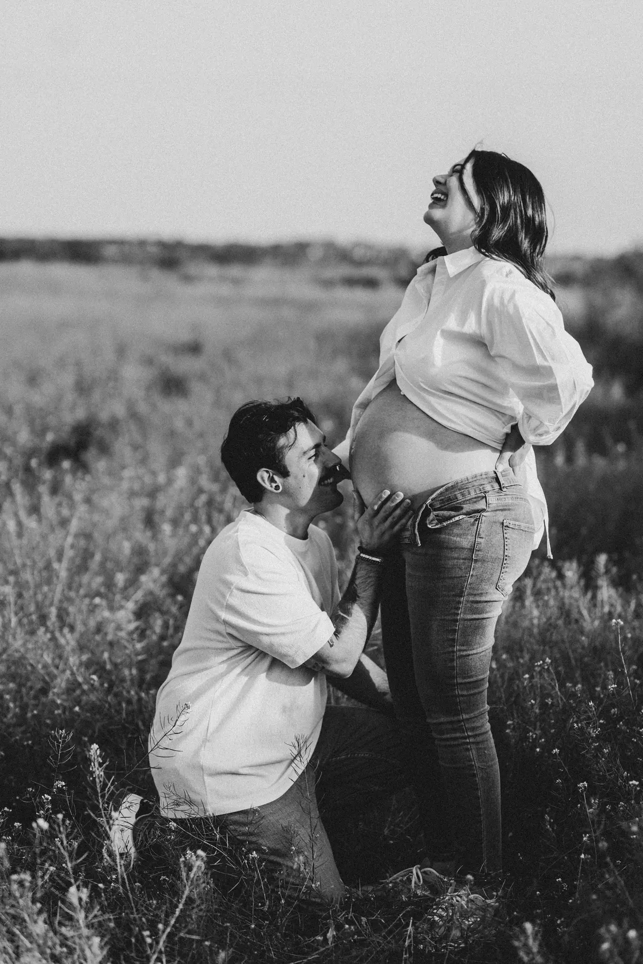 Futuro papá besando la tripa en el campo, en blanco y negro