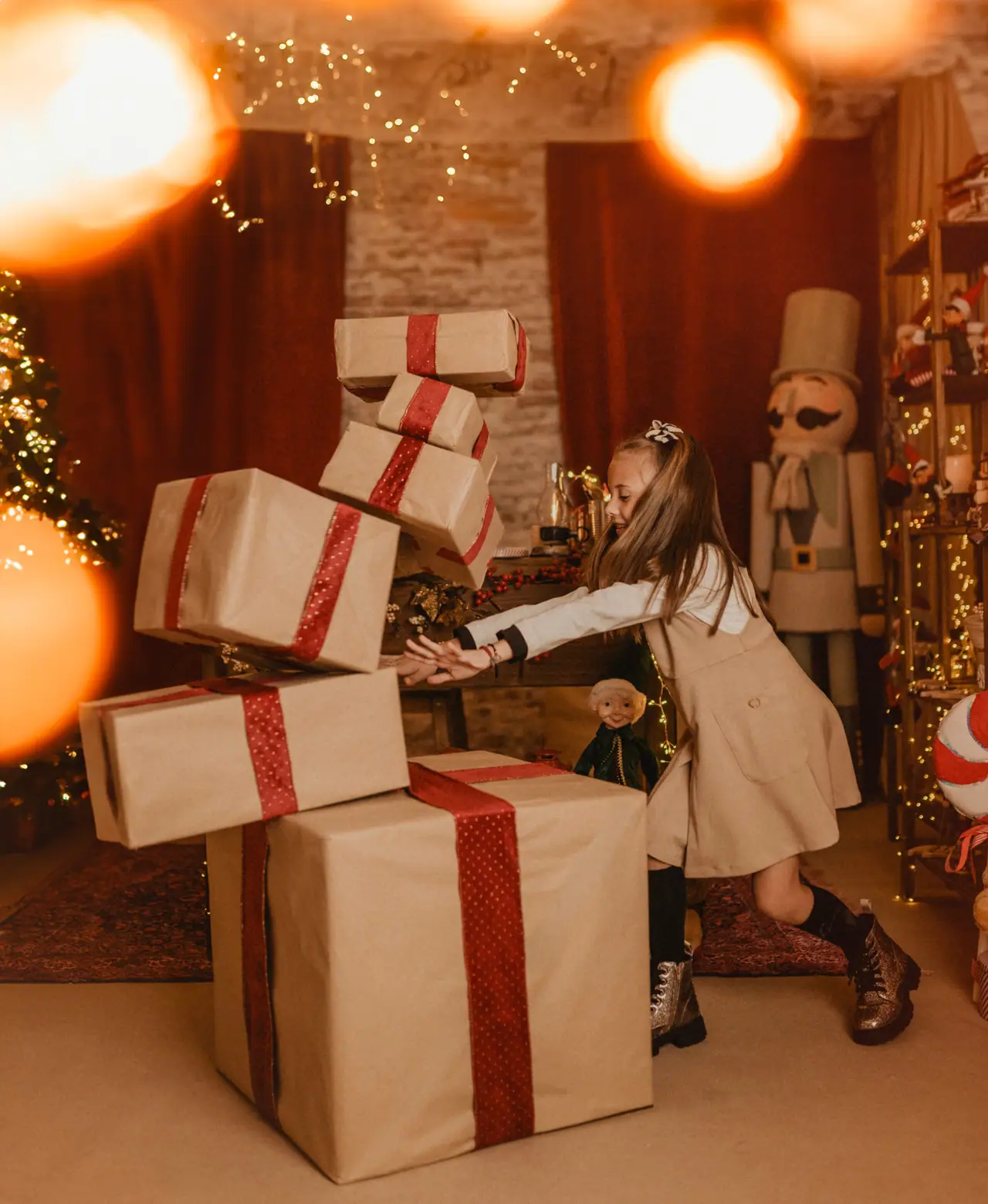 Niña empujando una torre de regalos en el set navideño del estudio