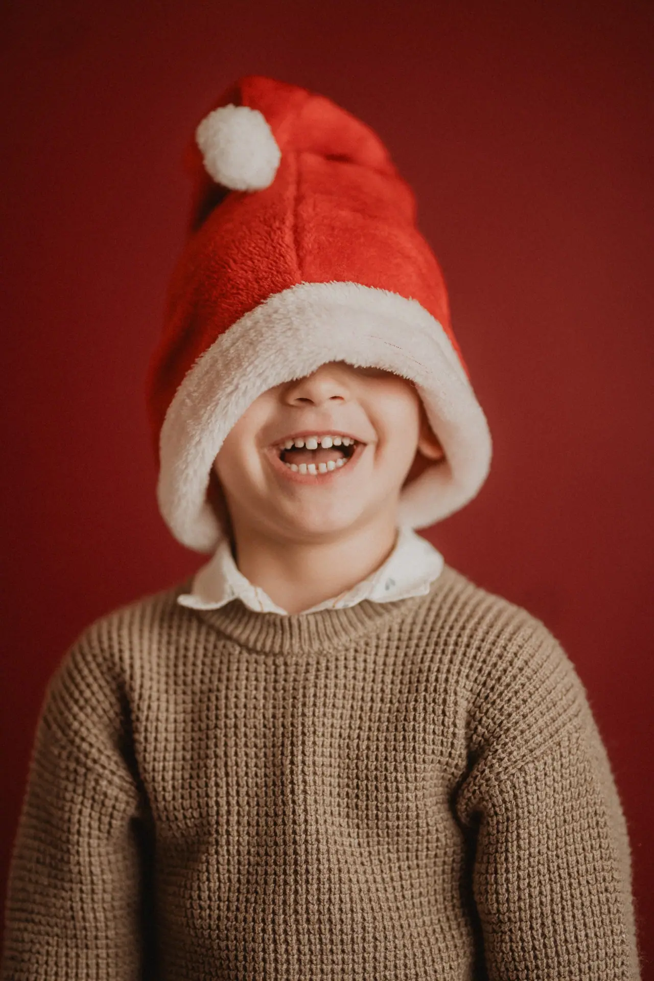 Niño riendo con el gorro de Papá Noel tapándole los ojos