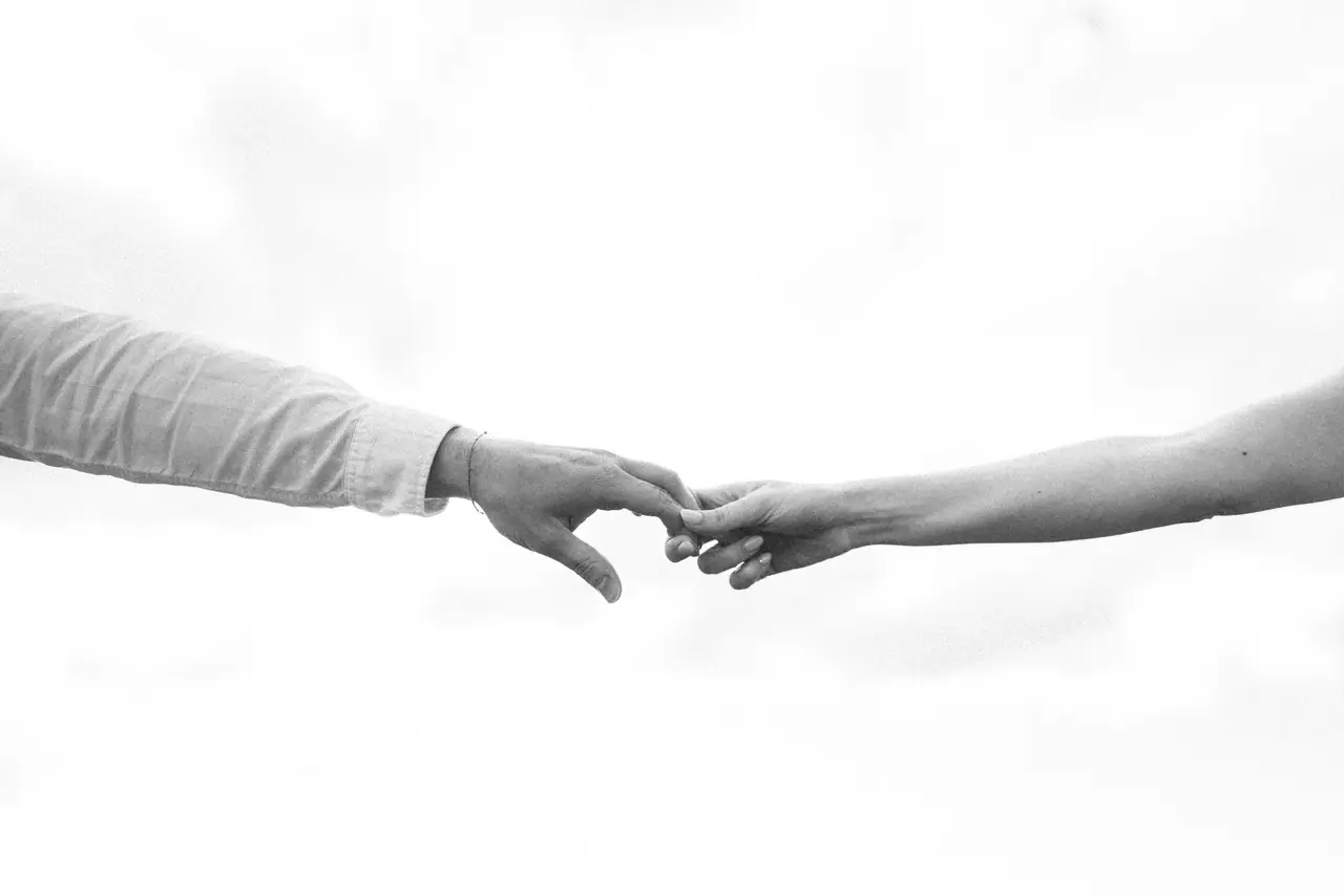 Manos de dos novios a punto de tocarse, en blanco y negro